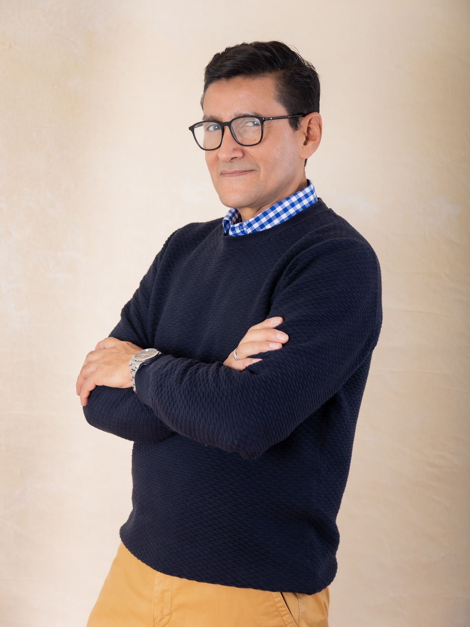 Henry Flores con suéter azul y brazos cruzados